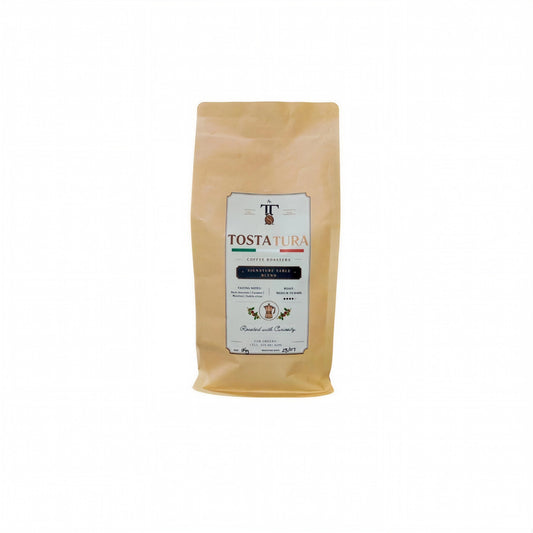 A 1Kg bag of Tostatura Coffee Roasted whole bean coffee in a light brown kraft paper pouch with a white and black label, set against a plain white background.